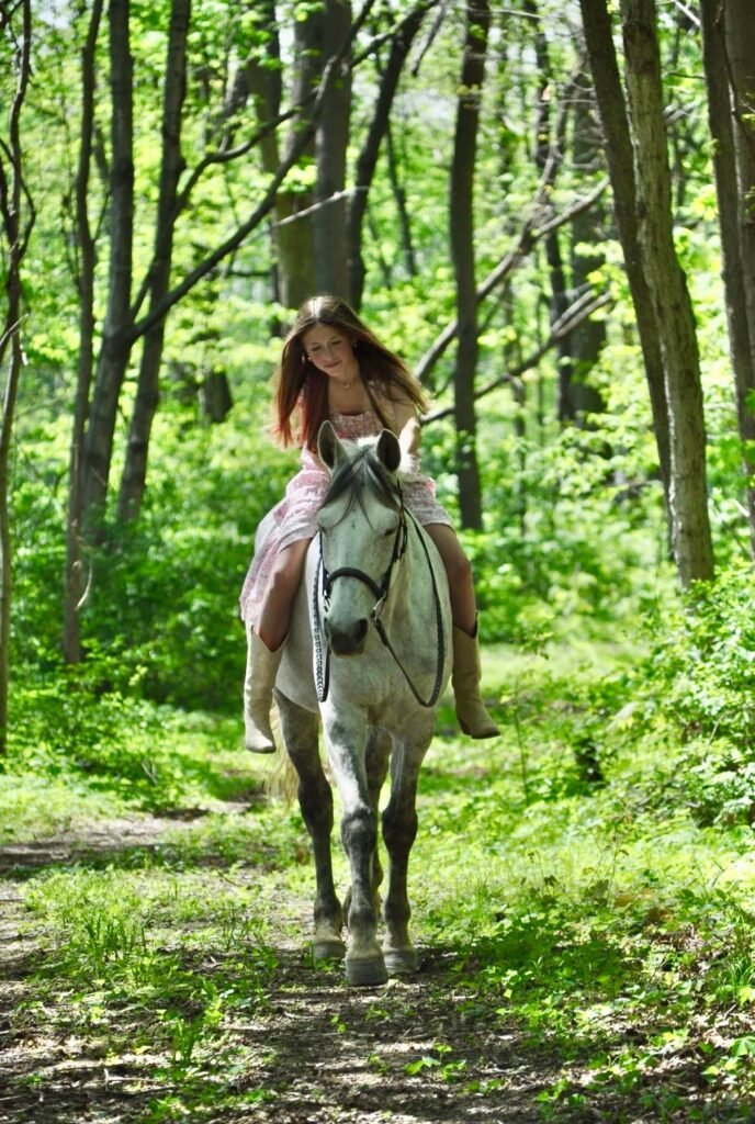 Ava riding Vienna on a wooded trail