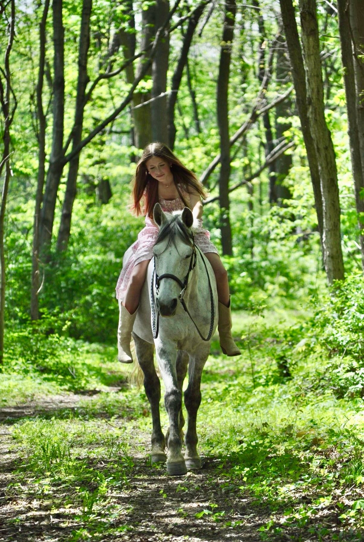 Ava riding Vienna on a wooded trail